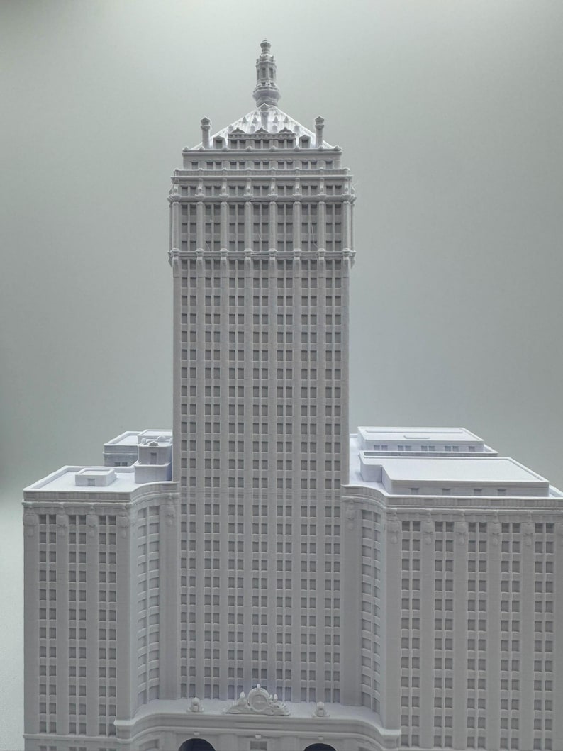 Puede incluir: Maqueta arquitect&oacute;nica gris claro de un rascacielos. El edificio presenta m&uacute;ltiples pisos con numerosas ventanas, una corona detallada y varias alas inferiores. El modelo es una representaci&oacute;n de un dise&ntilde;o de edificio cl&aacute;sico.