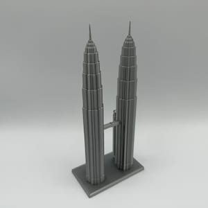 May include: A gray 3D printed model of the Petronas Towers in Kuala Lumpur, Malaysia. The model features two tall towers connected by a skybridge.