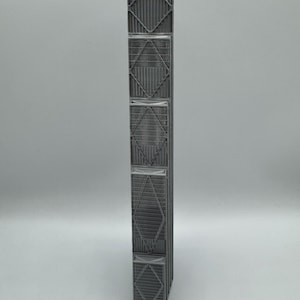 May include: A tall, narrow, gray rectangular column featuring a repeating structural pattern of vertical slats and diagonal cross-bracing. The object has a matte finish and a modular design with five distinct stacked sections, each framed by rigid borders.