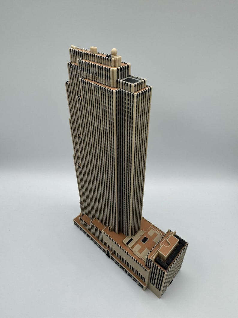 Puede incluir: Maqueta arquitect&oacute;nica detallada de un rascacielos. El modelo presenta una torre alta y rectangular con l&iacute;neas verticales y una parte superior de varios niveles. La base del edificio tiene un dise&ntilde;o detallado. La paleta de colores es principalmente beige y marr&oacute;n.