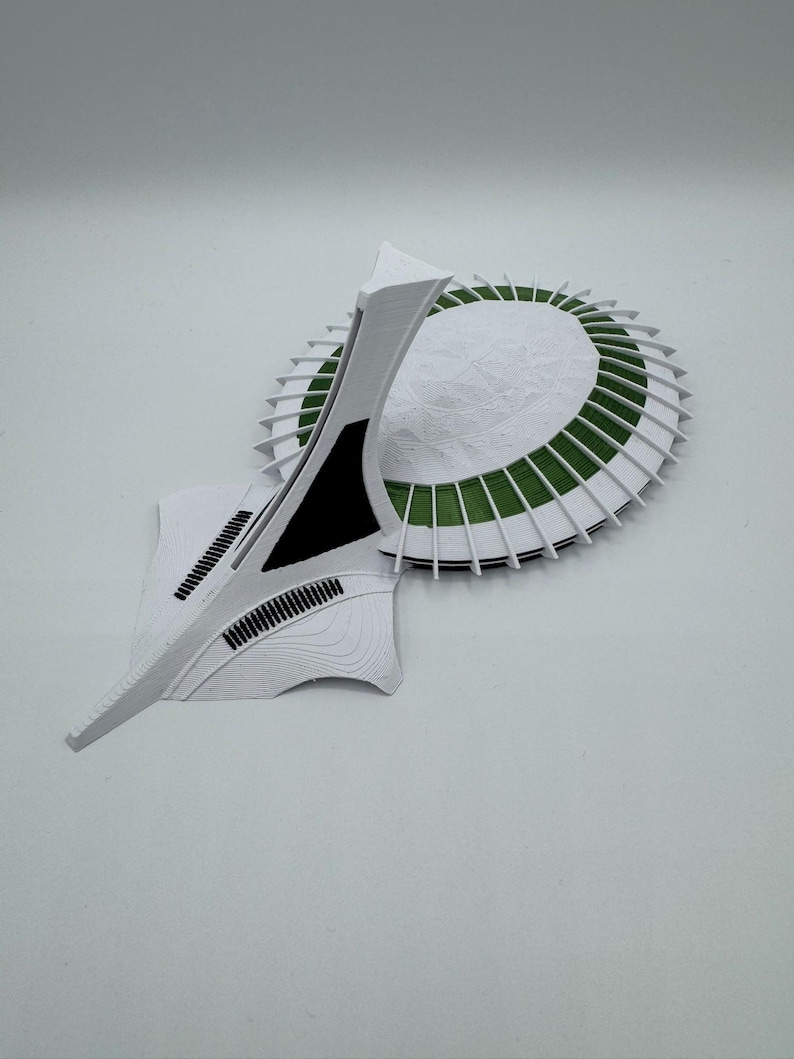 Puede incluir: Maqueta arquitect&oacute;nica abstracta en blanco y verde. El dise&ntilde;o incluye una base circular con detalles verdes y una estructura alta y angular. Los detalles en negro y la superficie texturizada completan la est&eacute;tica moderna.