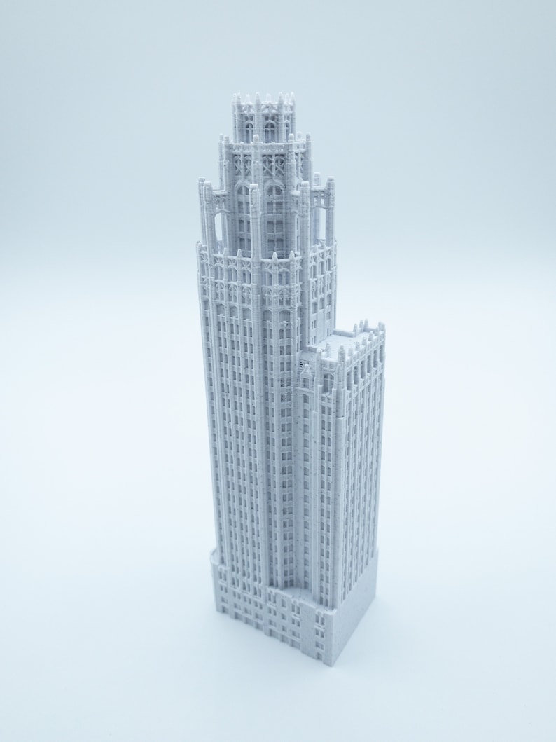 May include: A white 3D printed model of a tall, slender building with a decorative top and many windows.