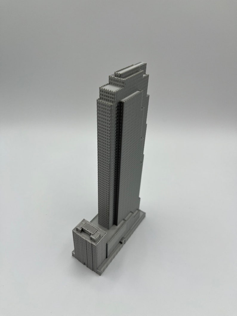 May include: A gray 3D printed model of a skyscraper with a rectangular base and a tall, narrow tower. The tower has a series of setbacks and a flat roof.
