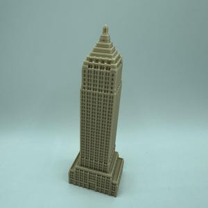 Puede incluir: Un modelo en miniatura beige de un rascacielos con un techo puntiagudo y muchas ventanas.