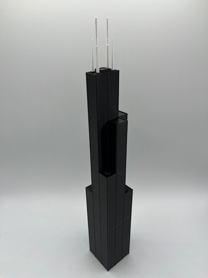 May include: A black 3D printed model of a skyscraper with white antenna details.