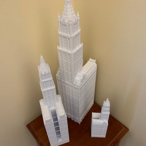 K&ouml;nnte beinhalten: Drei wei&szlig;e 3D-gedruckte Modelle von Wolkenkratzern. Das h&ouml;chste Geb&auml;ude ist etwa 30 cm hoch, das mittlere Geb&auml;ude etwa 20 cm hoch und das kleinste Geb&auml;ude etwa 13 cm hoch.