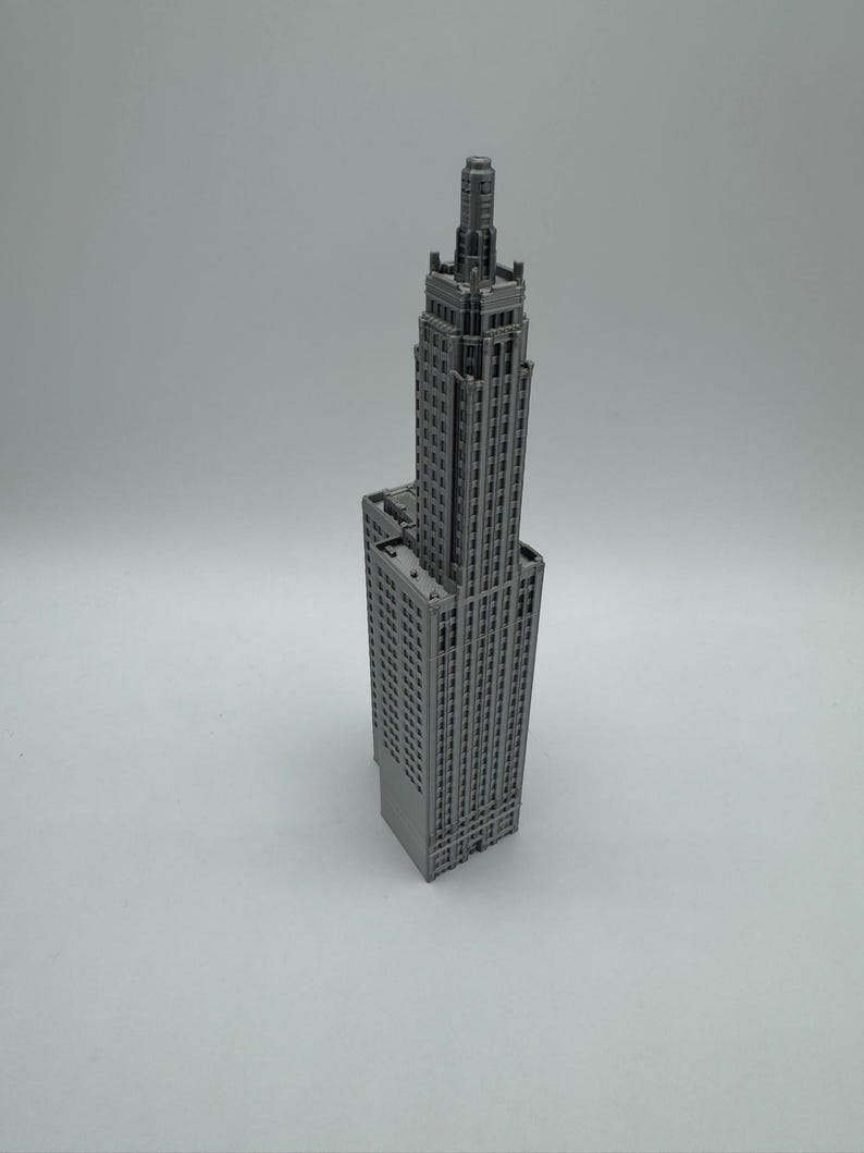 May include: A grey model of a tall, slender skyscraper with a pointed roof and many windows.