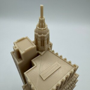 Pu&ograve; includere: Un modello 3D stampato di un edificio con un'alta guglia appuntita. L'edificio &egrave; realizzato in plastica beige chiaro e ha una facciata dettagliata.