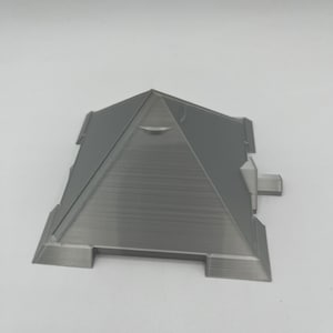 Puede incluir: Modelo de pir&aacute;mide gris impreso en 3D con parte superior plana y base rectangular. La pir&aacute;mide tiene una superficie texturizada y est&aacute; dise&ntilde;ada con detalles arquitect&oacute;nicos. El modelo es una forma geom&eacute;trica s&oacute;lida.
