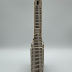 May include: A beige, three-dimensional model of a skyscraper featuring a stepped architectural design. The structure displays a repeating pattern of rectangular windows across its vertical facade, culminating in a narrow, tiered tower section.