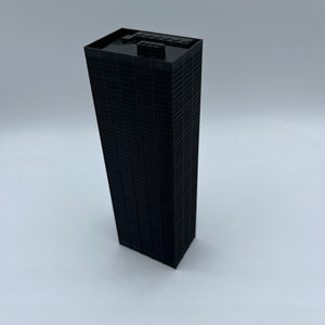 May include: A black Lego model of a skyscraper building.