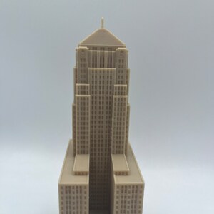 May include: A beige 3D printed model of a tall building with a pointed roof and many windows.