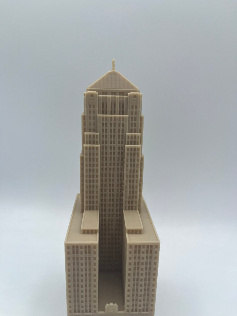 May include: A beige 3D printed model of a tall building with a pointed roof and many windows.