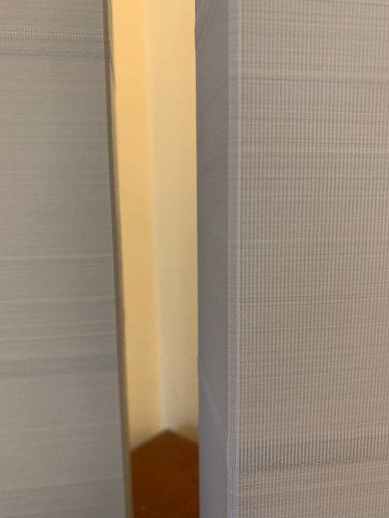 May include: Close-up of two grey textured surfaces, likely fabric, with a narrow gap between them. The surfaces have a subtle pattern of small lines.