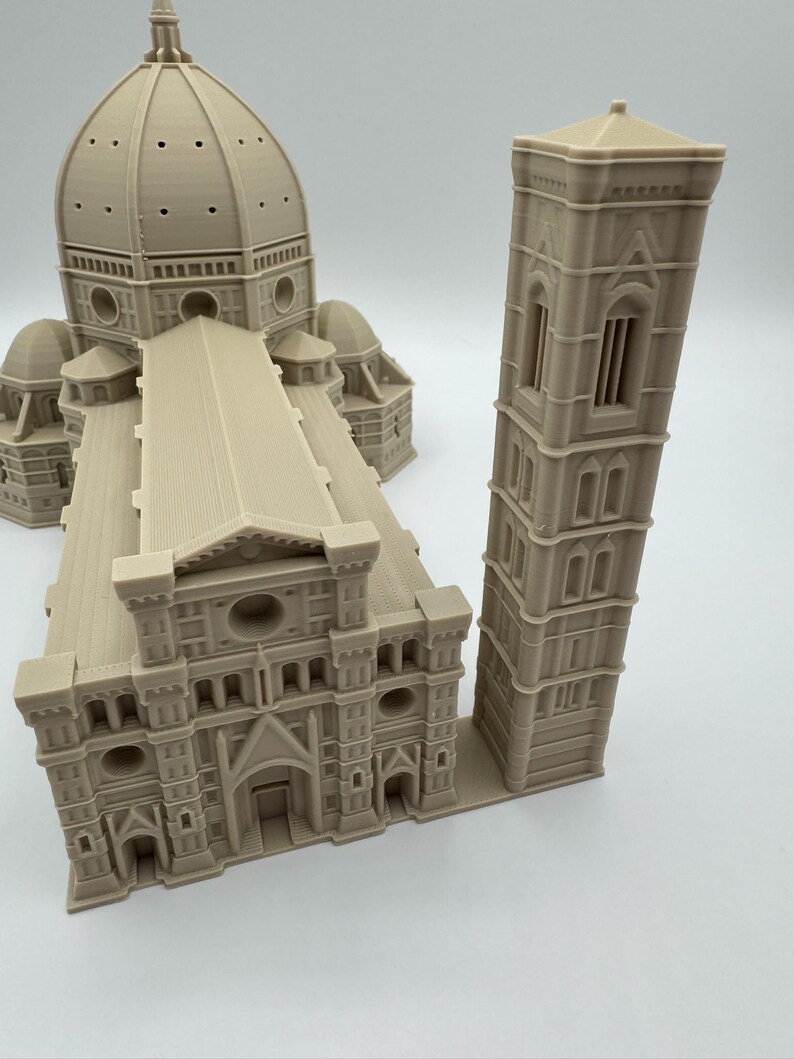 May include: A beige 3D-printed model of the Florence Cathedral, featuring the iconic dome, facade, and bell tower. The model showcases architectural details, including arched windows and intricate rooflines. The model is a detailed replica of the famous Italian landmark.
