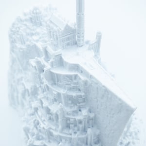 May include: A white 3D printed model of a castle with a tall tower and intricate details. The model is made of plastic and has a smooth, matte finish.
