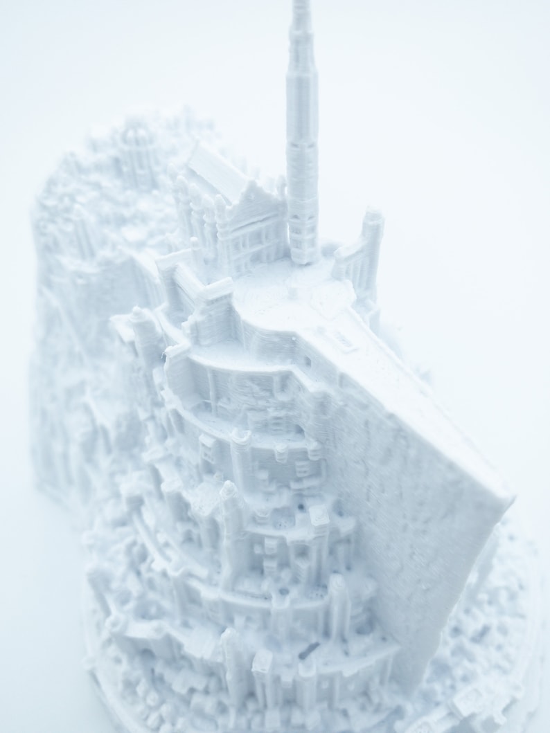 May include: A white 3D printed model of a castle with a tall tower and intricate details. The model is made of plastic and has a smooth, matte finish.