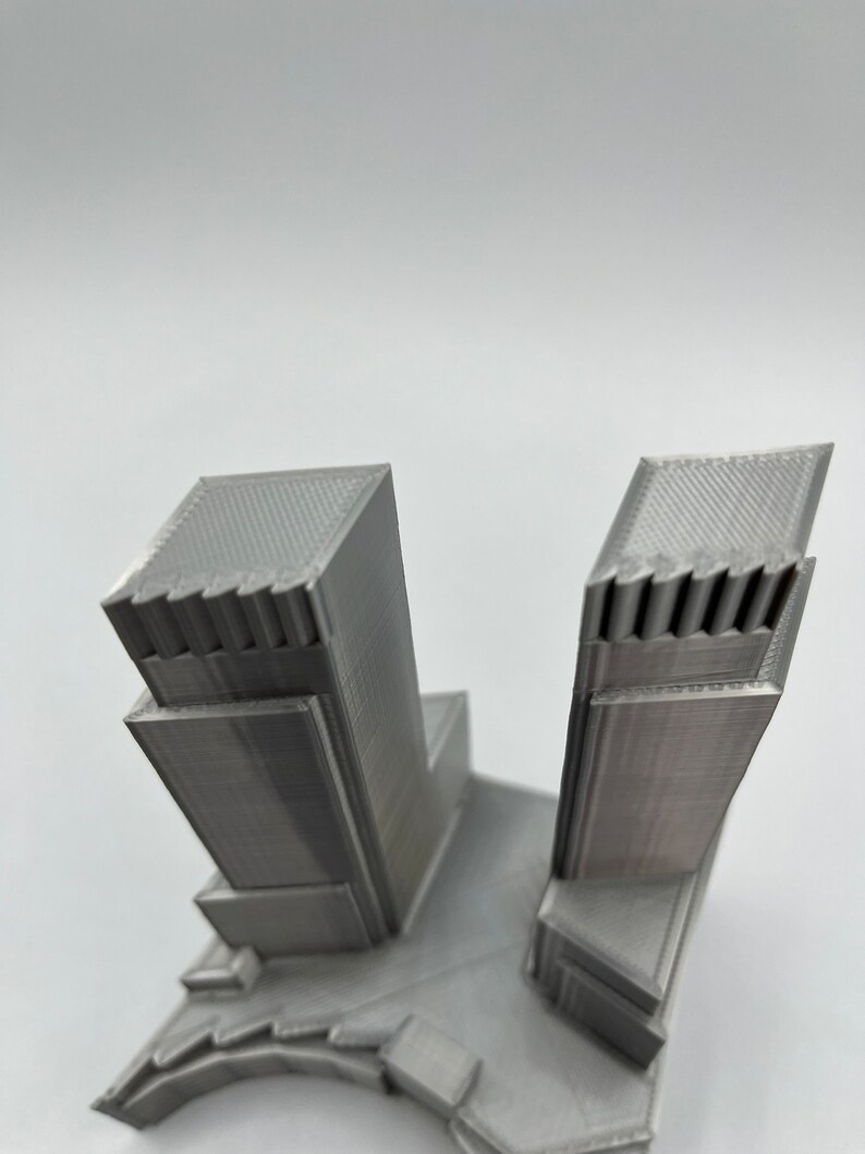 Op de afbeelding: Een 3D-geprint model van een paar wolkenkrabbers met een grijze afwerking.
