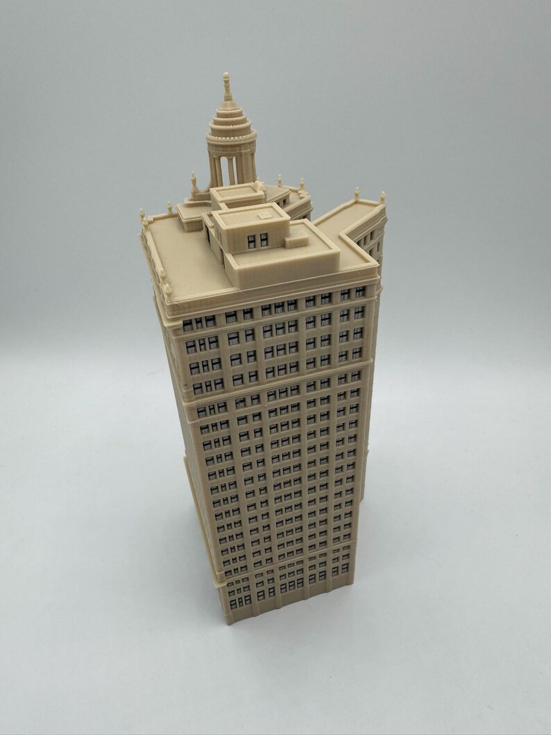 Op de afbeelding: Een beige miniatuurmodel van een hoog gebouw met een koepelvormig dak en veel ramen.