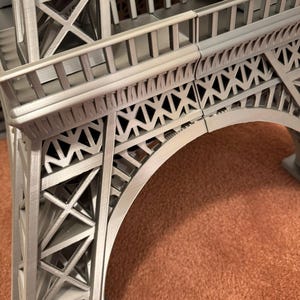 May include: A detailed, gray Eiffel Tower model, showcasing the intricate lattice structure and architectural details. The model features the iconic arch and multiple levels, capturing the essence of the Parisian landmark. The model is made of a gray material.