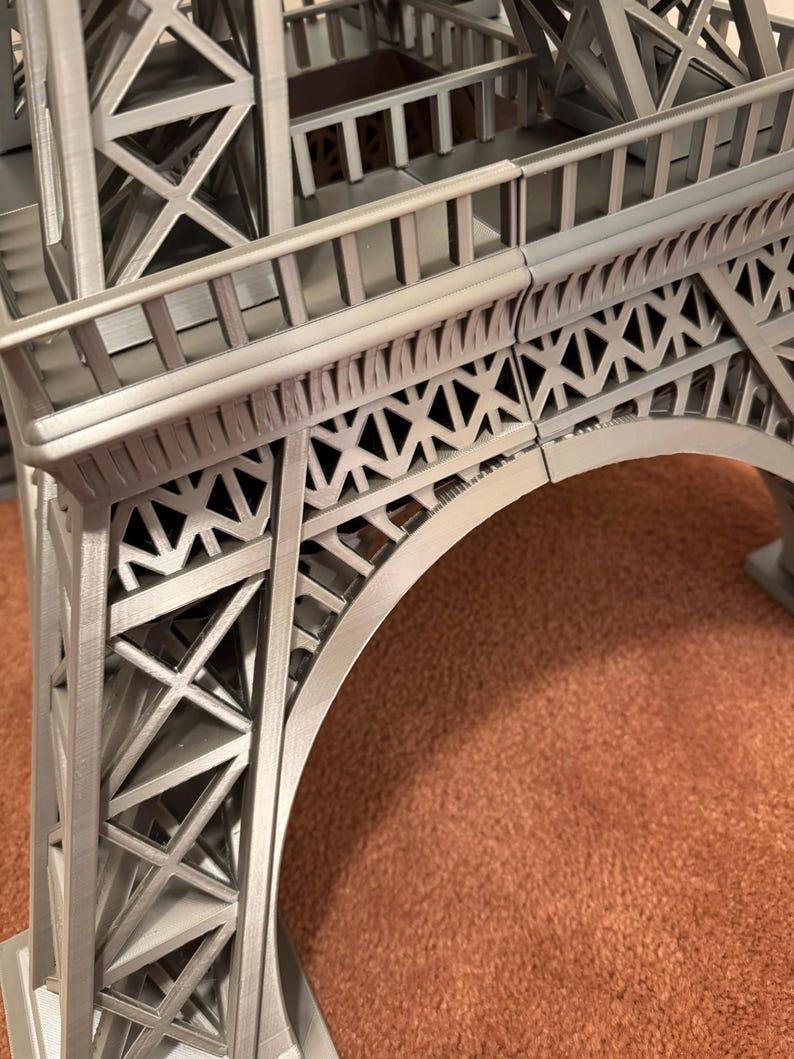 May include: A detailed, gray Eiffel Tower model, showcasing the intricate lattice structure and architectural details. The model features the iconic arch and multiple levels, capturing the essence of the Parisian landmark. The model is made of a gray material.