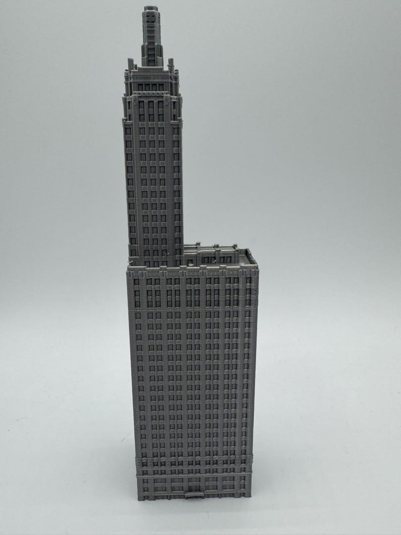 May include: A grey 3D printed model of a tall skyscraper building with many windows.