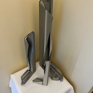 May include: Three gray 3D printed models of skyscrapers, the tallest is about 12 inches tall, the other two are about 6 inches tall.