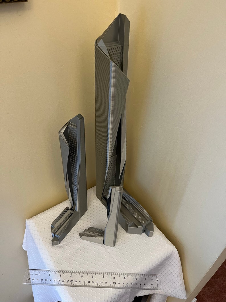 May include: Three gray 3D printed models of skyscrapers, the tallest is about 12 inches tall, the other two are about 6 inches tall.