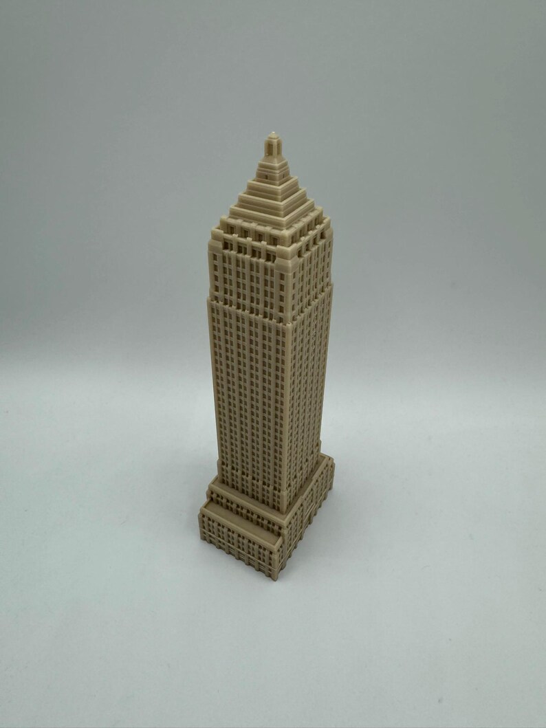 Puede incluir: Un modelo en miniatura beige de un rascacielos alto con un techo puntiagudo y muchas ventanas.