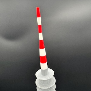 May include: A 3D-printed, abstract sculpture featuring a red and white striped pole atop a stack of translucent, circular platforms. The pole has a red tip and alternating red and white bands. The platforms are stacked, creating a unique, modern art piece.