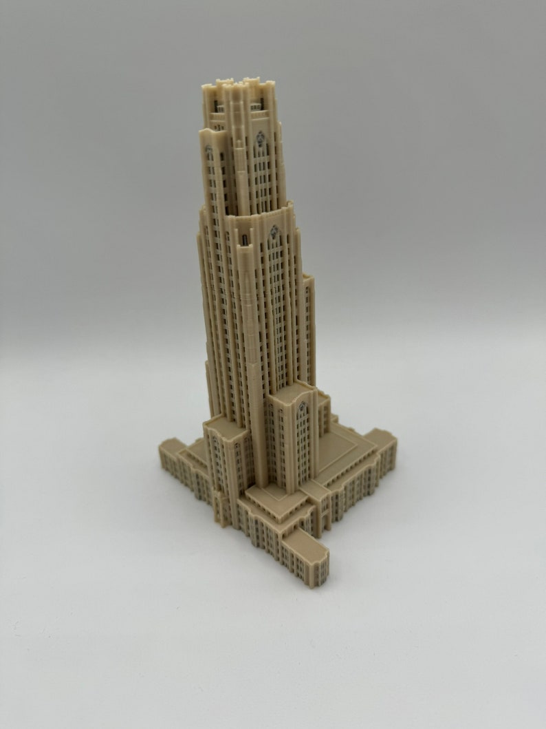 May include: A beige 3D printed model of a tall building with a square base and a tower with many windows.