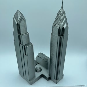 May include: A 3D printed model of two skyscrapers, likely representing the Comcast Center and One Liberty Place in Philadelphia, Pennsylvania. The model is made of gray plastic and is approximately 8 inches tall.