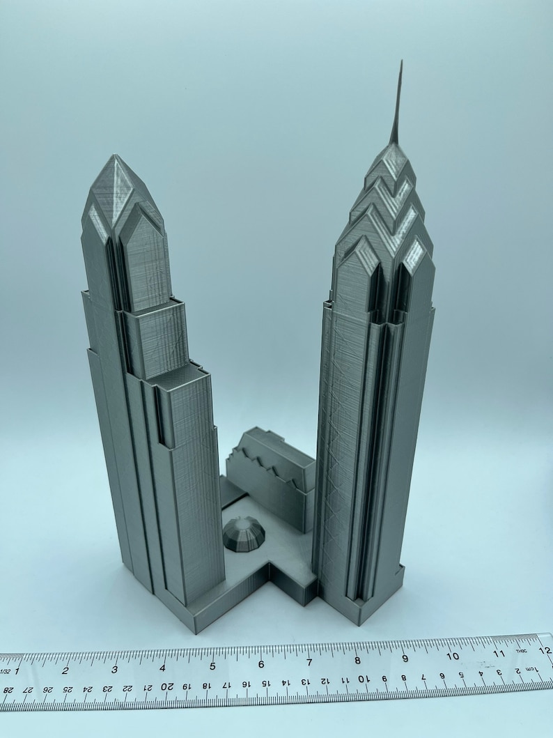 May include: A 3D printed model of two skyscrapers, likely representing the Comcast Center and One Liberty Place in Philadelphia, Pennsylvania. The model is made of gray plastic and is approximately 8 inches tall.