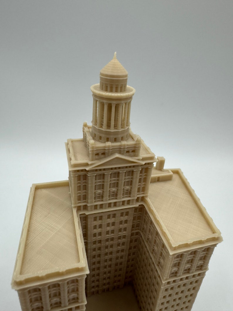 May include: A 3D printed model of a tall building with a domed roof. The building is beige and has many windows. The model is detailed and realistic.