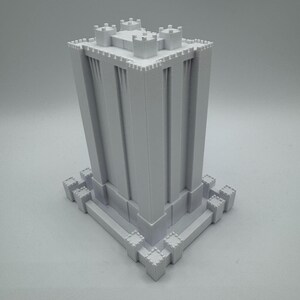 May include: A white 3D printed model of a tall, rectangular tower with crenellations and a flat roof. The tower is surrounded by a low wall with crenellations.