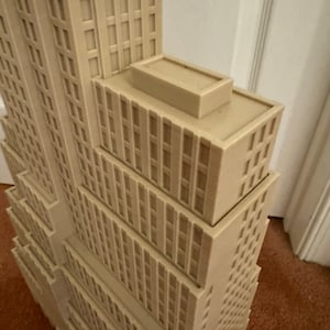Może przedstawiać: Beigeowy model 3D-drukowany wysokiego wieżowca z płaskim dachem.