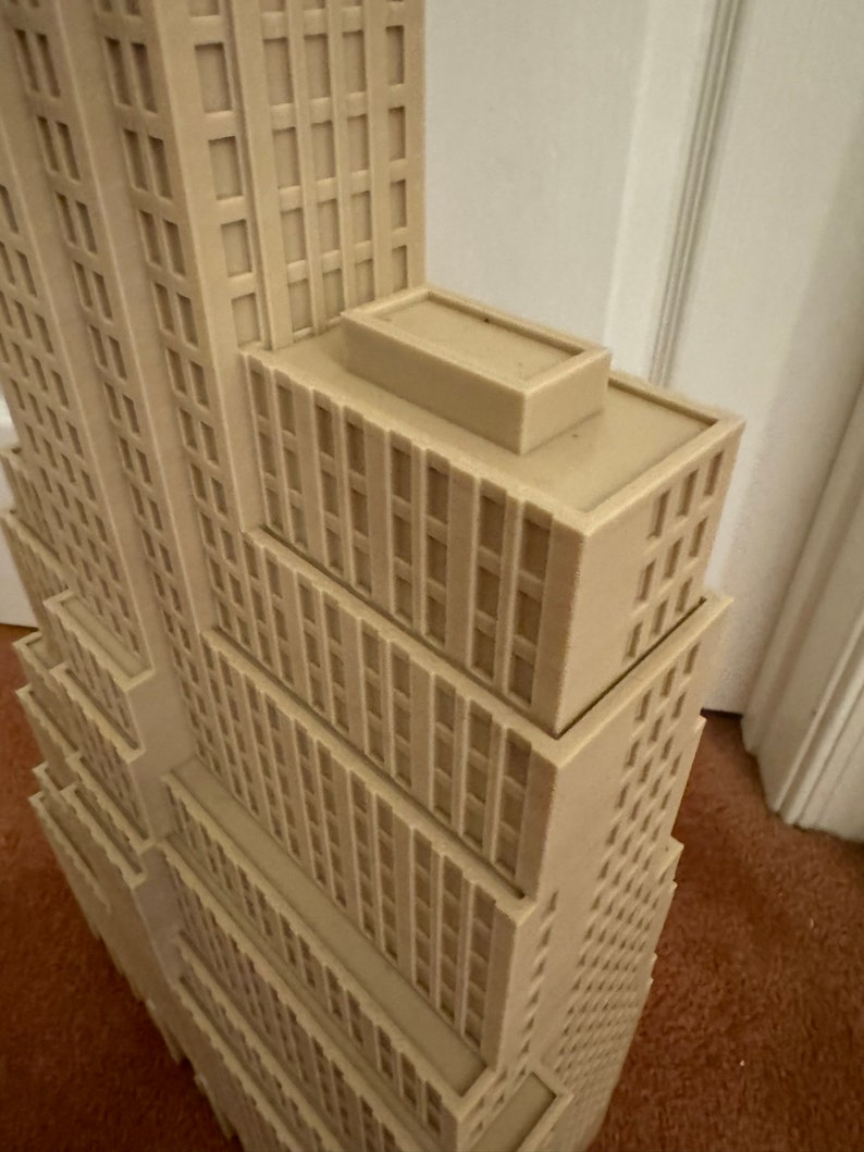 Może przedstawiać: Beigeowy model 3D-drukowany wysokiego wieżowca z płaskim dachem.