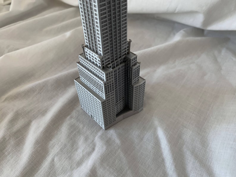 Puede incluir: Un modelo gris del Empire State Building, un famoso rascacielos de la ciudad de Nueva York.