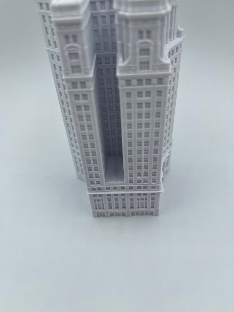 Op de afbeelding: Een wit 3D-geprint model van een hoog gebouw met een rechthoekige opening in het midden.