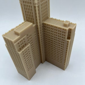 May include: A beige 3D printed model of a skyscraper with a detailed facade. The model is angled to show the side and front of the building.