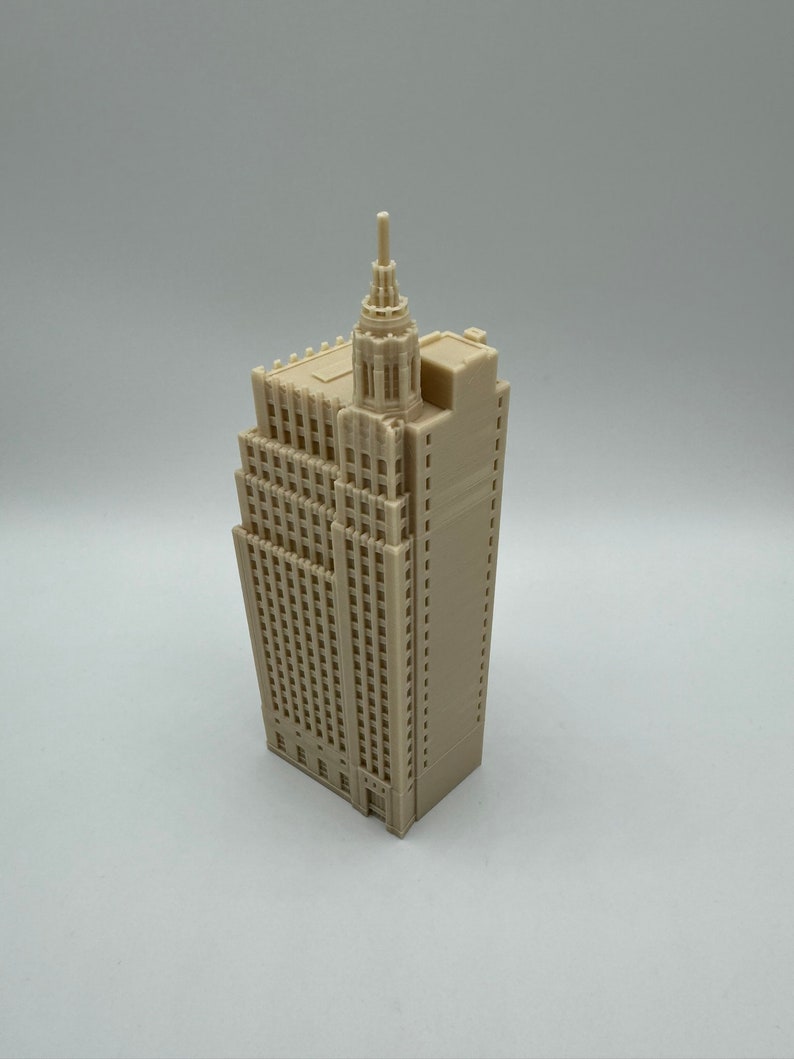 Pu&ograve; includere: Un modello 3D stampato in beige di un edificio alto con una guglia in cima. L'edificio ha molte finestre e una facciata dettagliata.