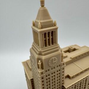 May include: A tan-colored architectural model of a building with a clock tower. The model has detailed windows, columns, and decorative elements. The clock on the tower shows the time as approximately 1:00.