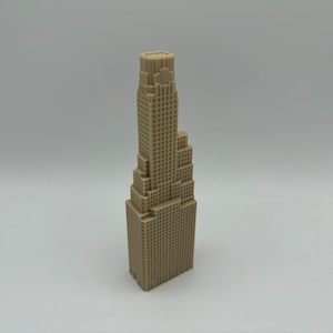 May include: A beige 3D printed model of a skyscraper with a stepped design. The model is made of plastic and has a smooth finish.