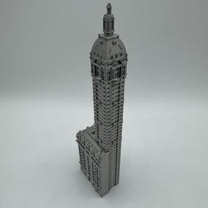 May include: A gray 3D printed model of a tall, ornate building with a domed roof.