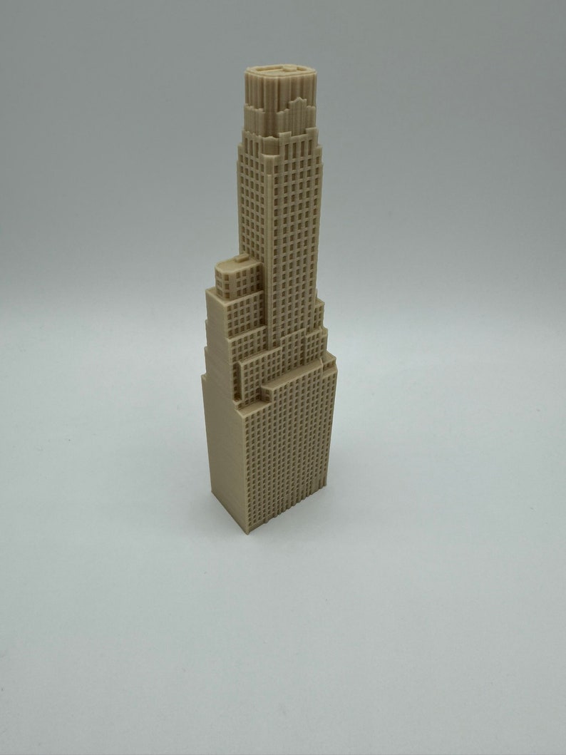 May include: A beige 3D printed model of a tall skyscraper building.