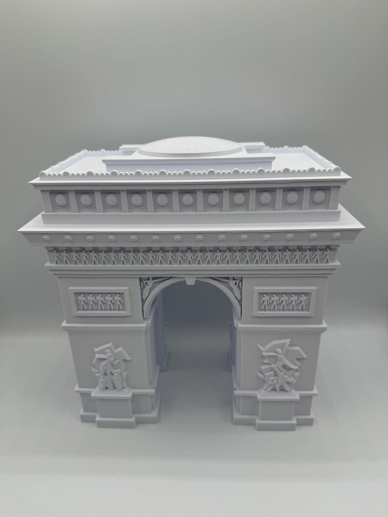 Może przedstawiać: Biała miniatura Łuku Triumfalnego. Model architektoniczny posiada szczeg&oacute;łowe rzeźbienia, w tym figury i elementy dekoracyjne. Łuk jest klasycznym zabytkiem.