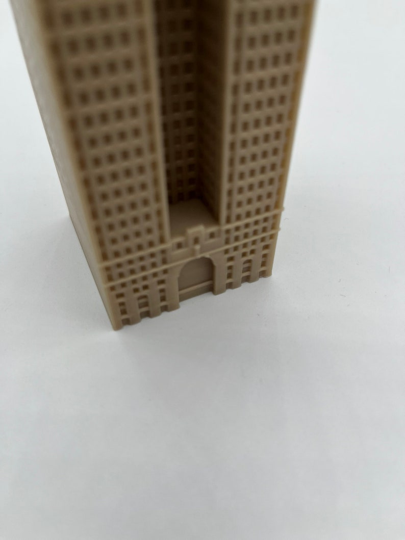 May include: A beige miniature building model with a detailed facade and a small entrance.
