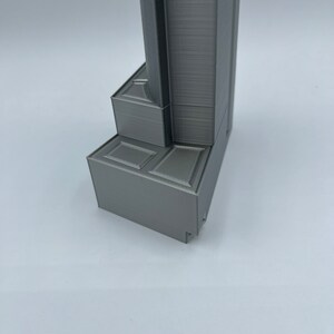 May include: A close-up of the base of a gray 3D printed model. The base is made up of several layers and has a textured surface.