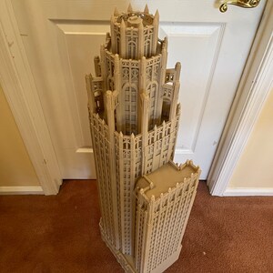 May include: A detailed model of a tall, beige building with intricate architectural details. The model is made of a smooth, light brown material and has a slightly textured surface.