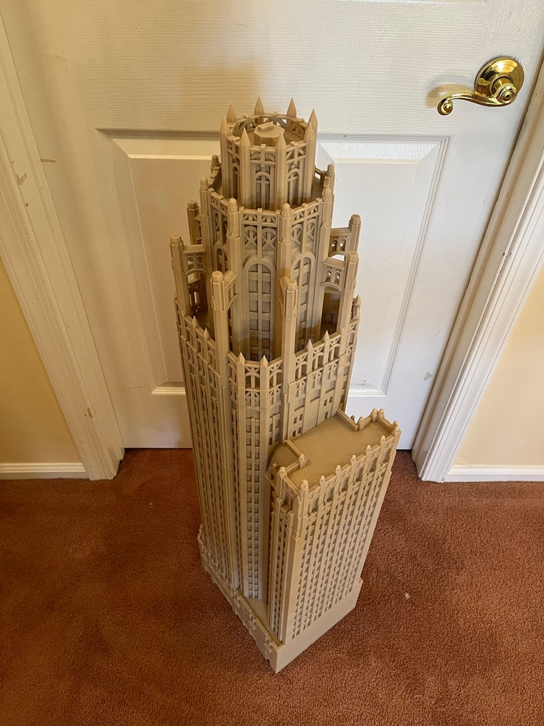 May include: A detailed model of a tall, beige building with intricate architectural details. The model is made of a smooth, light brown material and has a slightly textured surface.